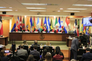 members of a court sitting with flags of countries of the world behind them