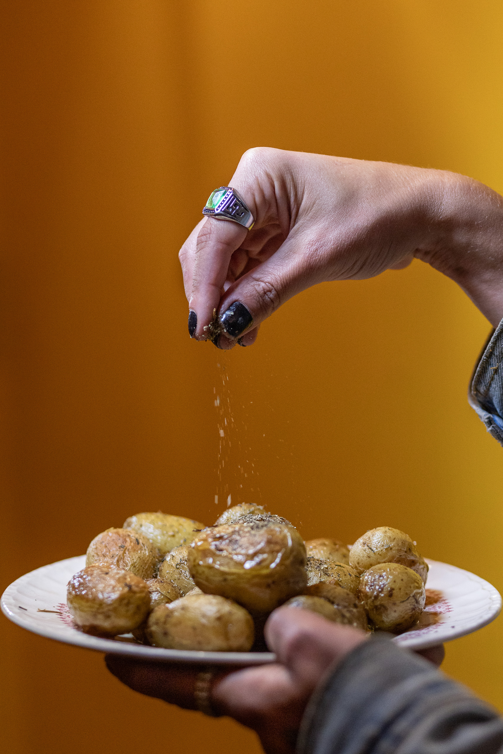 a hand sprinkling salt over a plate of potatoes