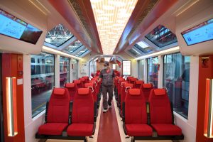 man walking down aisle between rows of red seats