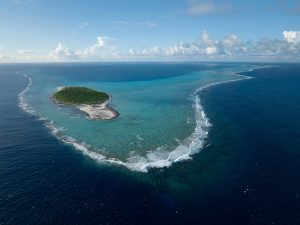 Aerial view of a lush green island surrounded by deep blue ocean waters